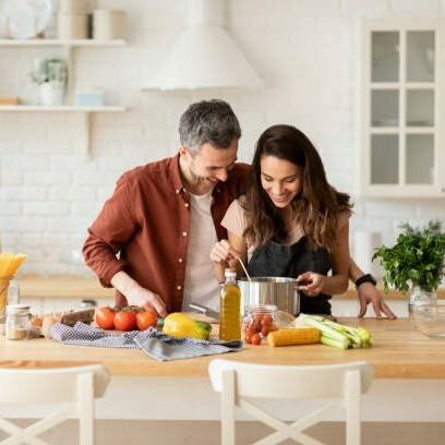 Happy man and woman preparing dinner or lunch from fresh health ingredient. Husband hugging smiling wife. Couple rejoice at resulting delicious dish. Laughing family domestic portrait. Cook on kitchen